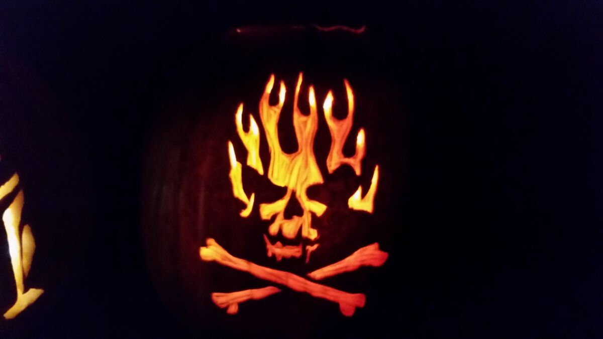 A pumpkin carved with a flaming skull.