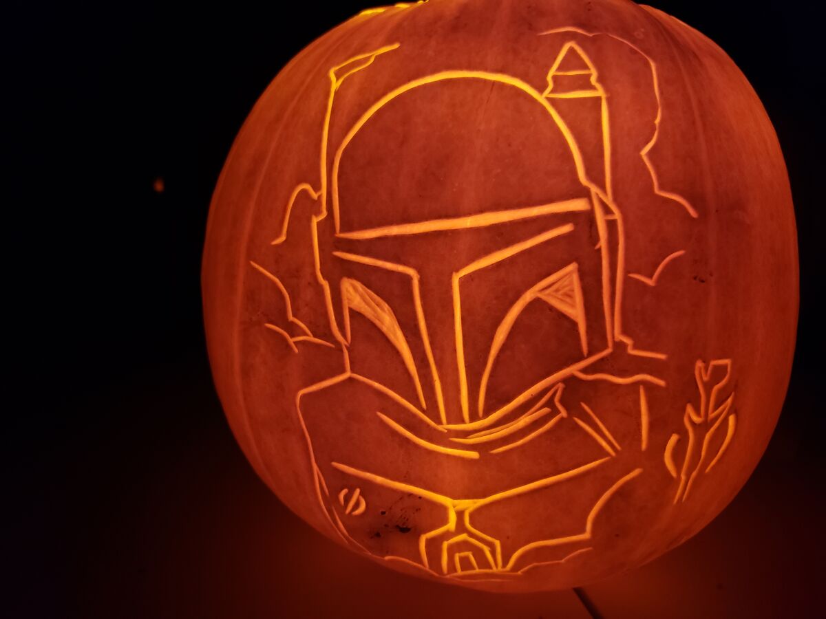 A pumpkin carved with Boba Fett from Star Wars.