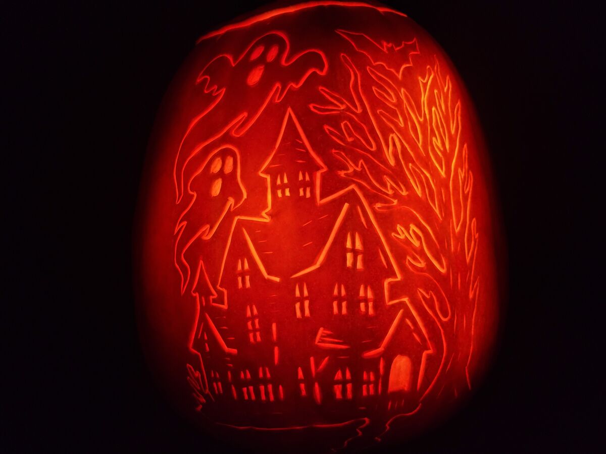 A pumpkin carved with a haunted house.
